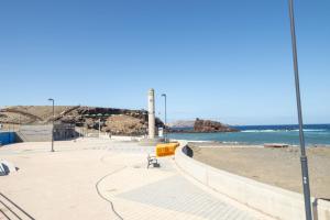 een strand met een bank en de oceaan bij Lightbooking El Burrero in Ingenio