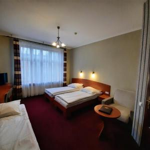 a hotel room with two beds and a table at Hotel Kazimierz II in Kraków