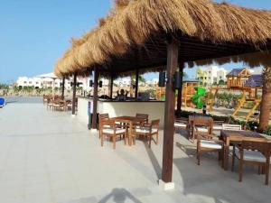a restaurant with tables and chairs and a thatched roof at British style in Makadi Heights in Hurghada
