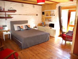 una camera con un letto in una stanza con pavimenti in legno di Les Gîtes du Couvent Alternatif a Camlez