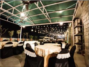 un comedor con mesas, sillas y luces en Hotel Badrika Inn, en Rewa