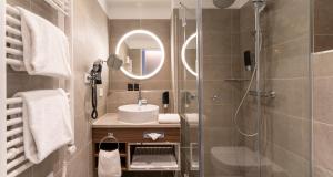 a bathroom with a sink and a shower with a mirror at PLAZA Premium München in Munich +57 photos