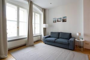 a living room with a blue couch and windows at Vienna Central Panorama in Vienna