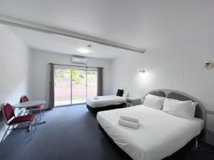 a hotel room with two beds and a table and chairs at The Grampians Motel in Halls Gap