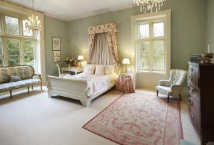 um quarto com uma cama, uma cadeira e janelas em The Old Rectory - Norfolk em North Tuddenham