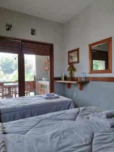 1 dormitorio con 2 camas, espejo y ventana en Dalem Arum (for women only) en Bandung