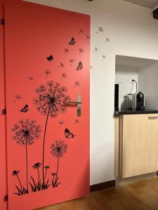 a kitchen with a red door with butterflies and dandelions at Sirogn House in Gordola