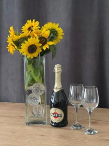a vase with a bottle of wine and two glasses at Apartament na Piaskach in Ostrowiec Świętokrzyski