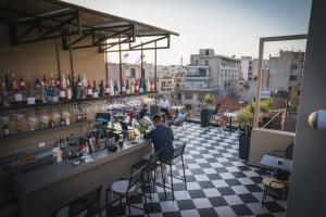 a man sitting at a bar on a rooftop at Pure Hotel by Athens Prime Hotels in Athens