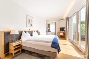 a bedroom with a large bed and large windows at Swiss Quality Turmhotel Victoria in Davos