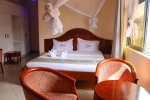 a bedroom with a bed with two chairs and a table at Two Oceans Hotel Voi in Voi