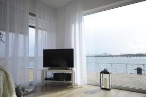 ein Wohnzimmer mit einem TV und einem großen Fenster in der Unterkunft Ferienwohnung OstseeBrise in Olpenitz