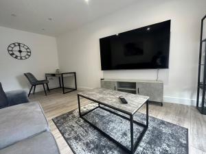 sala de estar con TV de pantalla plana grande en la pared en Apartment In Luton Town Centre, en Luton