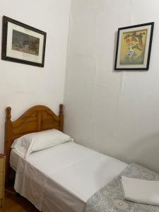 sypialnia z łóżkiem i 2 zdjęciami na ścianie w obiekcie Pensión Teruel w Barcelonie