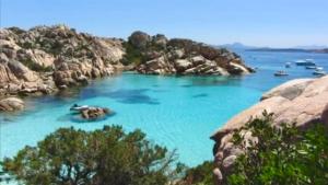 a body of water with rocks and boat in it w obiekcie Alloggio incantevole Costa Smeralda w mieście Porto Pozzo