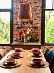 una mesa de madera con platos en una habitación con ventanas en Slapen bij de Brug, 