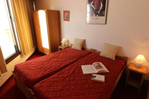 ヴァル・トランスにあるTrois Vallées Appartements VTIのベッドルーム1室(赤いベッド1台、本2冊付)