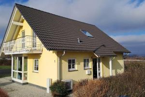 a yellow house with a black roof at Mawo Lodge in Lohfelden