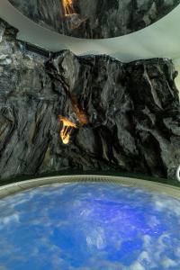 a large pool of water in a room with a rock wall at Hotel Saalbacher Hof in Saalbach-Hinterglemm
