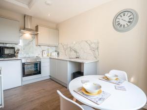 a kitchen with a white table and a clock on the wall at Hawthorn Cottage in Richmond +2 photos