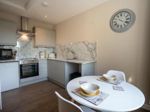 a kitchen with a white table and a clock on the wall at Hawthorn Cottage in Richmond
