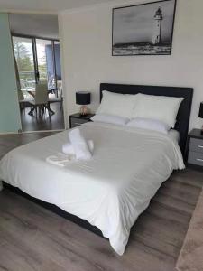 a large bed with white sheets and pillows in a bedroom at The Entrance Superb Apartment The Entrance NSW with Ocean - Lake Views in The Entrance