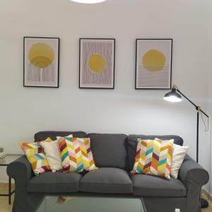 uma sala de estar com um sofá e três fotografias na parede em Apartamentos Alcazaba em Málaga