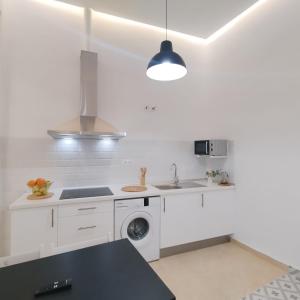 uma cozinha branca com um lavatório e uma máquina de lavar roupa em Apartamentos Alcazaba em Málaga
