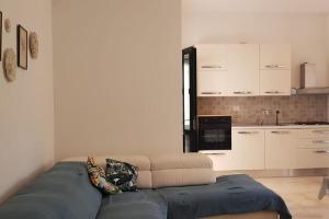 a living room with a blue couch and a kitchen at Villa tra gli ulivi in San Pietro in Bevagna