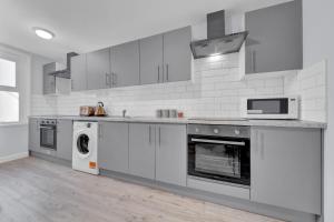 a white kitchen with a stove and a microwave at Lovely 1-Bed Studio in West Drayton in West Drayton
