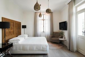 a white bedroom with a bed and a chair at The Drisco Hotel Tel Aviv - Relais & Châteaux in Tel Aviv