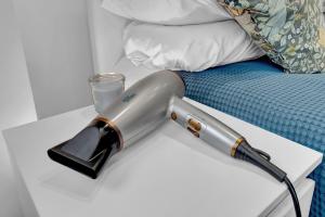 a blow dryer on a bed next to a glass at Captivating 1-Bed Studio in West Drayton in West Drayton