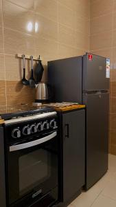 a kitchen with a black stove and a refrigerator at Home4u Fidji F2 in Cotonou