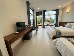 a hotel room with two beds and a desk with a television at Sandy Residence Sihanoukville in Sihanoukville