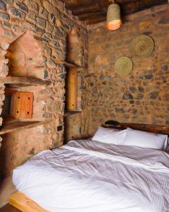 a bedroom with a bed in a stone wall at Hanging Terraces المدرجات المعلقة in Al ‘Aqar
