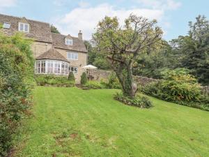 a house with a large yard with a tree at Grange Cottage in Woodchester