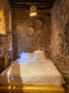 ein Schlafzimmer mit einem Bett in einer Steinmauer in der Unterkunft Hanging Terraces المدرجات المعلقة in Al ‘Aqar
