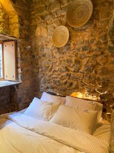 a bed in a room with a stone wall at Hanging Terraces المدرجات المعلقة in Al ‘Aqar