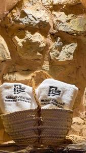 a basket with towels in front of a stone wall at Hanging Terraces المدرجات المعلقة in Al ‘Aqar