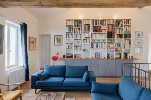 een woonkamer met een blauwe bank en boekenplanken bij Gîte des Pilliers in Belleville-sur-Saône