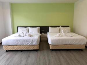 - 2 lits avec des draps blancs et des serviettes blanches dans l'établissement TT Dorf Hotel Matang, à Taiping