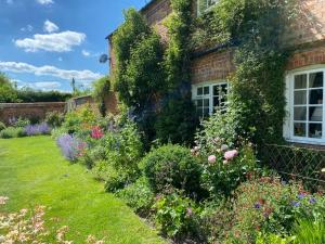 a garden in front of a house with flowers at Garden Cottage B&b in Penton Mewsey