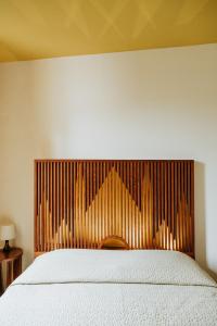 a bedroom with a white bed with a wooden headboard at La Magnolia in Orvieto
