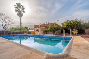 a swimming pool in front of a house with a palm tree at Villa Barby in Lliria
