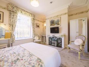 1 dormitorio con cama, TV y chimenea en Braemar Guest House en Buxton