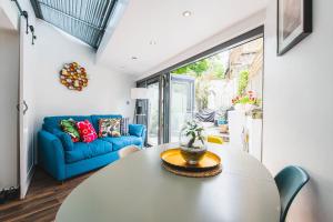 a living room with a table and a blue couch at Pass the Keys - Modern & Stylish Garden Home in Islington in London