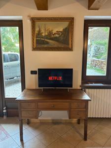 a tv on a wooden table in a room with windows at Casa Salada in Bagnolo Piemonte