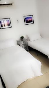 two white beds in a bedroom with two pictures on the wall at Zanzibar Town house in Ngambo
