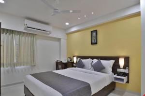 艾哈邁達巴德的住宿－Leo Hotel，一间卧室设有一张大床和黄色的墙壁