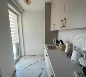 a white kitchen with a sink and a window at Apartament in Bochnia